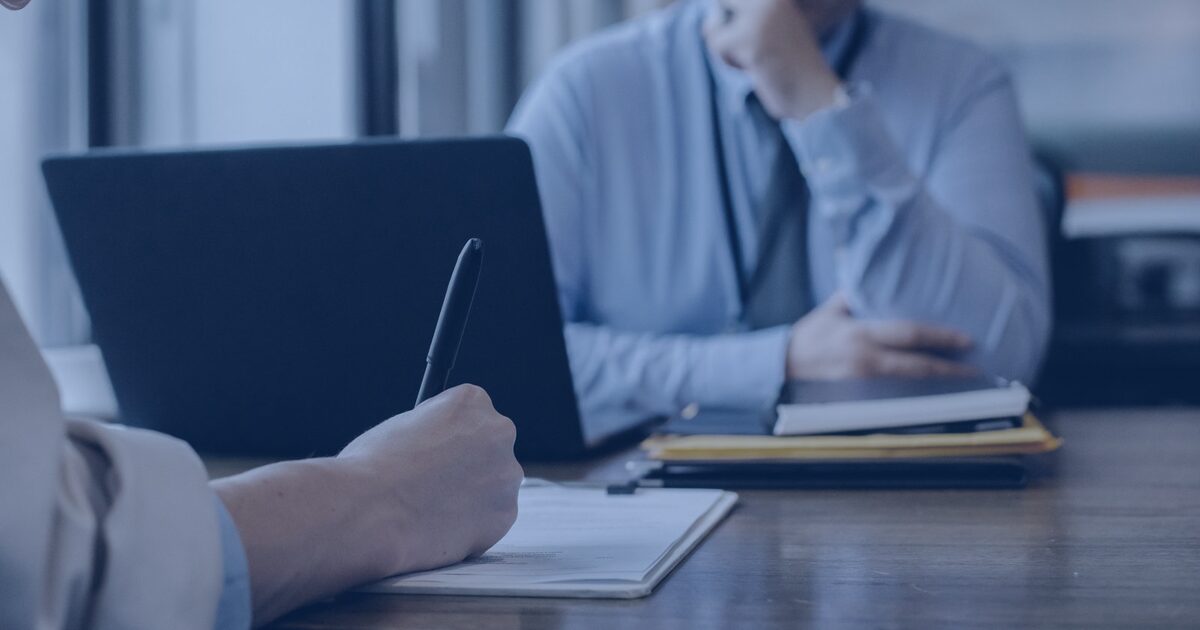 Pessoa assinando um contrato de compra e venda de imóvel sobre a mesa do escritório