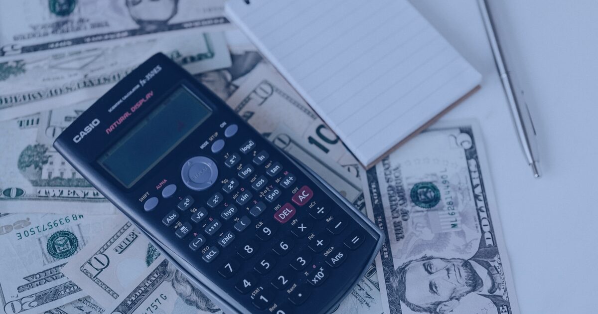 Calculadora, cédulas e planilhas de financiamento imobiliário sobre a mesa